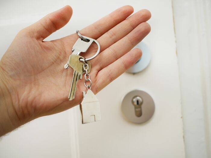 The featured image for the article titled: "Tax Tips for Property Investors: Deductions". The image includes a hand holding a set of silver and gold keys in front of a locked door.