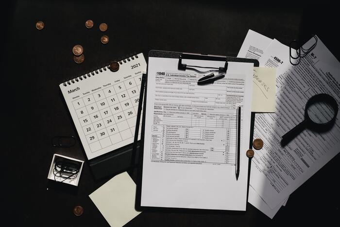 The featured image for the article titled: "tax tips for property investors-negative gearing". The image includes a flat lay of tax tools – a magnifying glass, calendar, calculator etc.